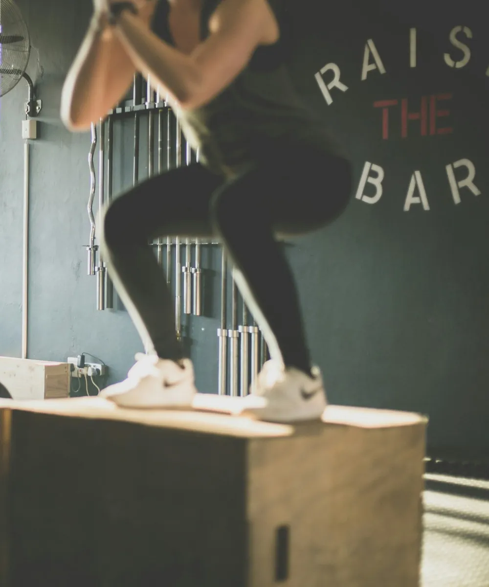 Atleta haciendo sentadilla sobre un cajón de salto de madera en un box