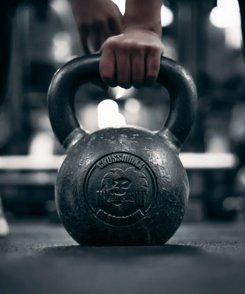 Atleta agarrando una kettlebell del suelo en un box