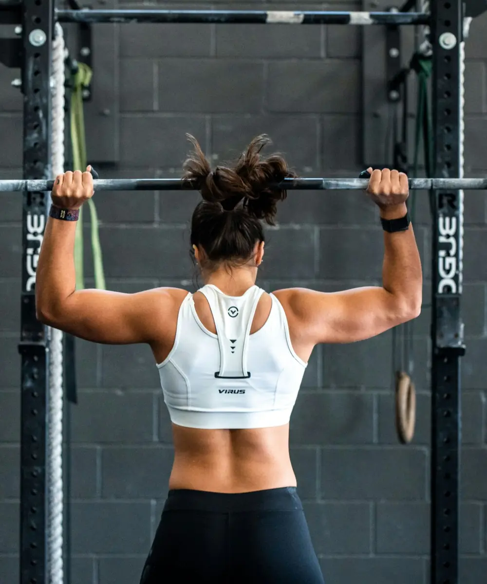 Mujer levantando una barra en el rack de un gimnasio