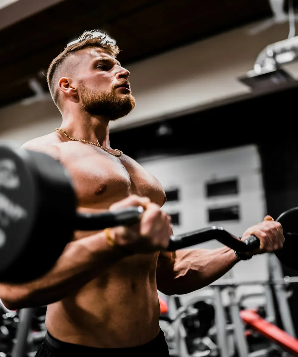 Hombre haciendo curl de bíceps con barra en un gimnasio